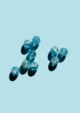Blue glass beads on a blue background. Hard shadow and reflection. DIY handmade gift. Abstract festive composition.の写真素材