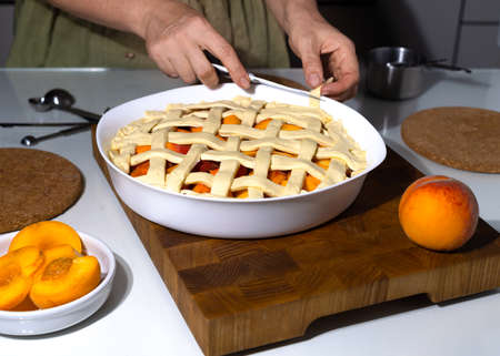 Housewife prepares fresh peach pie. Homemade baking process.の写真素材