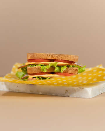 A traditional sandwich made from toasted bread slices, cheese, ham, fresh salad wrapped in organic beeswax paper.の写真素材