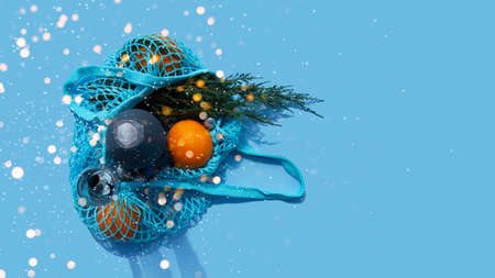 Christmas and New Year Composition. Blue String bag with champagne, oranges and branch of fir. Reusable shopping bag. Eco friendly mesh bags.の写真素材