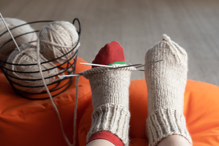 Woman knits warm woolen socks on knitting needles. Slow hobbies provide positive emotions, inspiration and relaxation.の写真素材