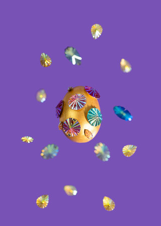 Easter egg decorated with beads on a purple background. levitation. Creative Easter concept. Veri...