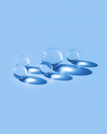 Little glass balls in direct sunlight on colorfull background. Long shadows. Monohrom composition.
