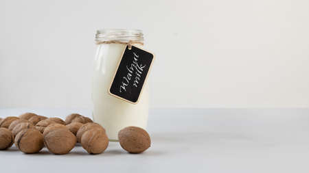 A bottle of dairy free alternative vegan walnut milk. Protein rich plant milks. Label with the name of the ingredient. On white table.の写真素材