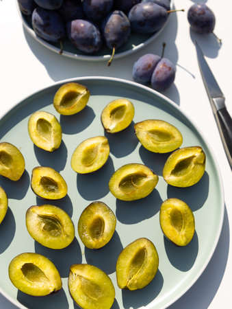 Whole and halves of a blue plums lie on a plate close-up. autumn harvest. Preparatory stage for making jam, home baking or freezing for the winter.の写真素材