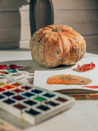 Drawing in watercolor in a sketchbook. Autumn still life with pumpkin and red leaf. Learning to draw at home. Creating content concept.の写真素材