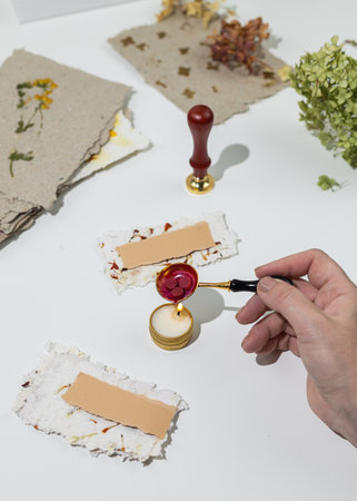 The process of creating wedding place cards from homemade recycled paper, pressed flowers and sealing wax. Personalized wedding name tags.の写真素材