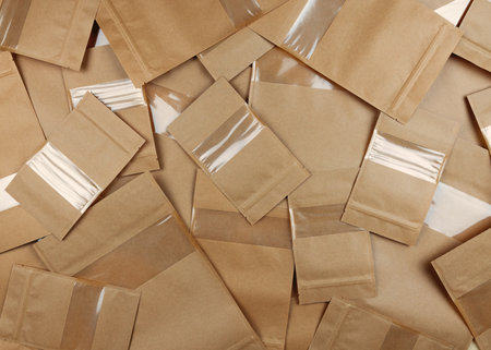 Brown kraft paper doypack bags with groceries front view on a yellow background. Packaging for foods and goods template mock-up. Packs with windows for weight products. top viewの写真素材