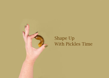 A woman's hand holds a pickle and shows an OK gesture. Concept of holiday Shape Up With Pickles Time. The name of the holiday on a green background.の写真素材