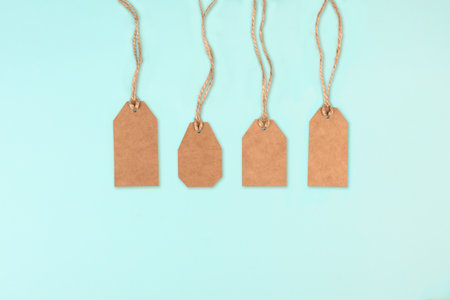 Brown kraft paper tags with jute rope on blue background. price label. sale discount concept. Copy space, flat layの写真素材