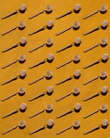 Pattern with Eco-friendly bamboo dishwashing brush with long wooden handle lying on yellow background. Creative concept of cleaning.の写真素材