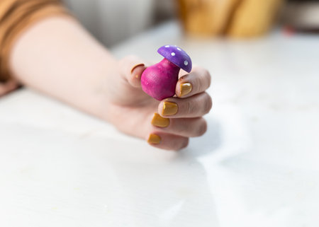 A woman paints wooden mushroom toys with acrylics. Cottagecore Mushroom interior decor aesthetics. For shelf or table display, for decorating houseplants.の写真素材