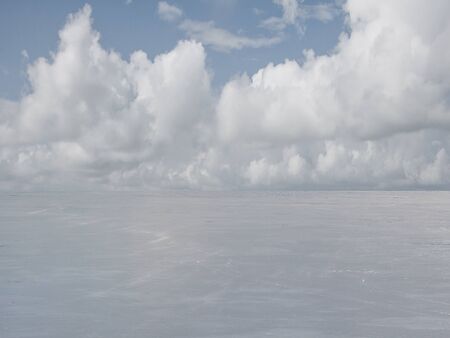 Frozen winter lake in the background of floating cloudsの写真素材