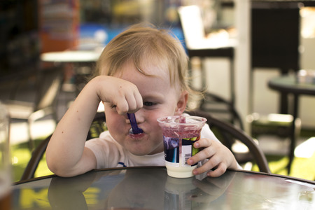 Child at the table & eating yogurtの写真素材