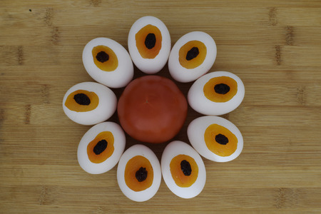 Tomato eggs dried apricots raisins in one flower on wooden plank kitchen compositionの写真素材