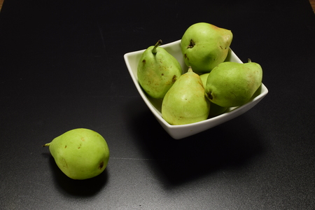 Green ripe pears in a white plate on a black backgroundの写真素材