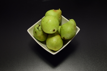 Green ripe pears in a white plate on a black backgroundの写真素材