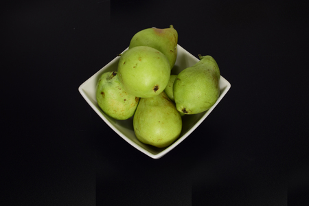 Green ripe pears in a white plate on a black backgroundの写真素材
