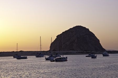Moored boats in Morro Bay are the foreground for Morro Rock at sunset.の写真素材