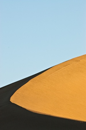 The early morning light hits the ridge line and peak of a sand dune in Mesquite Flat, Death Valley National Park, California.の写真素材