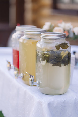 water from jug pouring into glass on wooden table outdoors