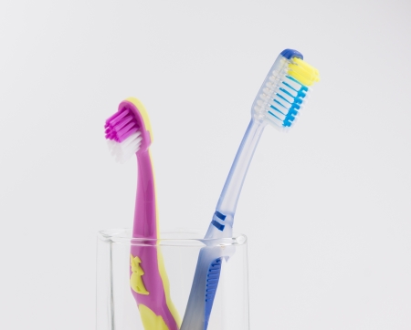 big and small toothbrushes in a glass on a white backgroundの写真素材