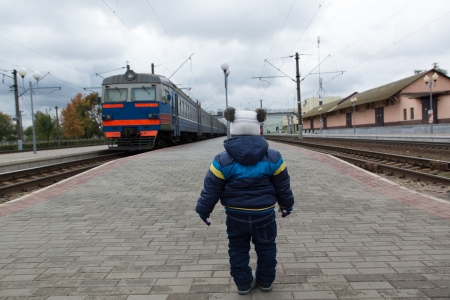 boy stands on the platform and looks after the departing trainの写真素材
