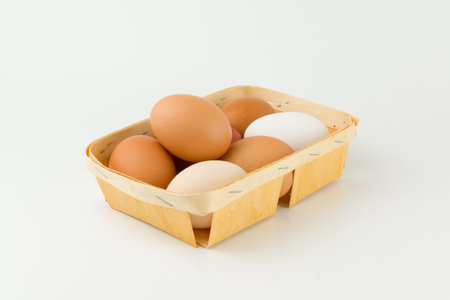 some fresh eggs lie in a wooden tray