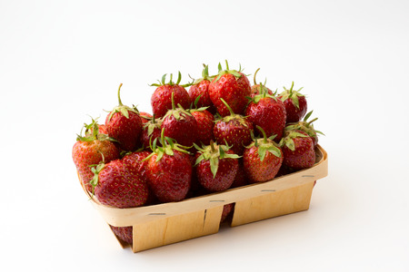 wooden box full of ripe juicy strawberry on a white backgroundの写真素材