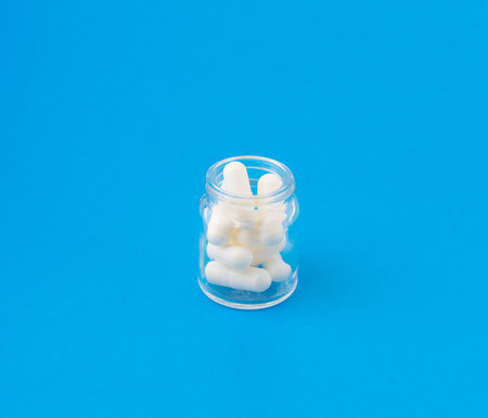 the small group of white tablets and pills is scattered on a surface