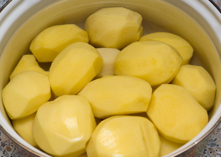 fresh peeled potatoes is in the water in the panの写真素材