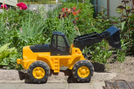 the plastic toy car costs against a bright flower bedの写真素材