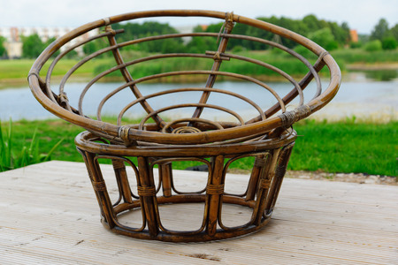 the chair weaved from rods of a rattan is on the bank of the lakeの写真素材