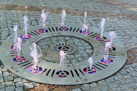 cheerful fountain on the sidewalk with color illuminationの写真素材