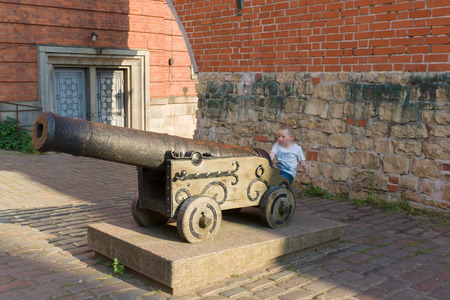 the little boy climbed on an ancient gun near a fortificationの写真素材