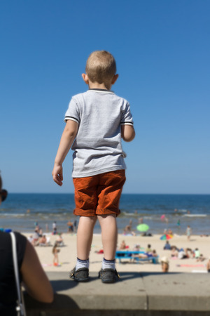 the boy in shorts looks from the embankment at the seaの写真素材