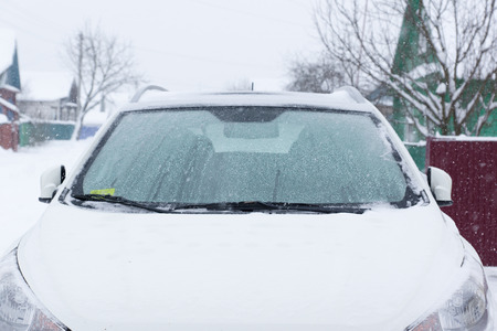 White car covered with snow during a blizzardの写真素材