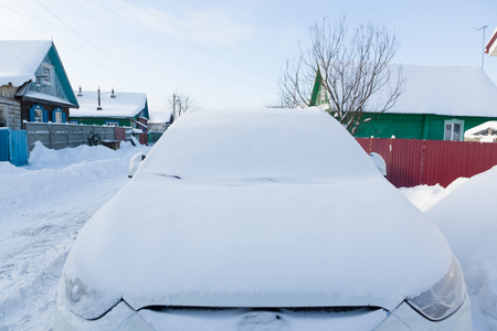 White car covered with snow during a blizzardの写真素材