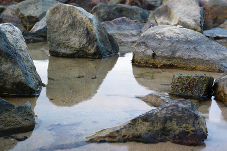huge old stones scattered on the beach of seaの写真素材