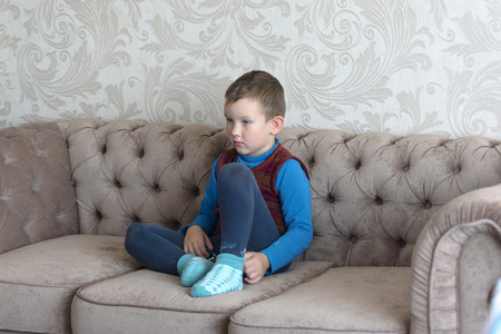 the boy with a sad kind of sitting on the couchの写真素材