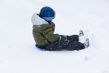 little boy in the winter riding with a snow hillの写真素材