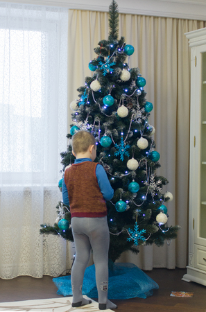 little boy decorates a Christmas tree beautiful Christmas decorationsの写真素材