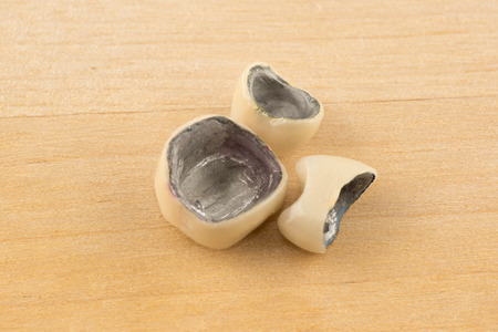 Large image of modern dental metal-ceramic crowns on a wooden backgroundの写真素材
