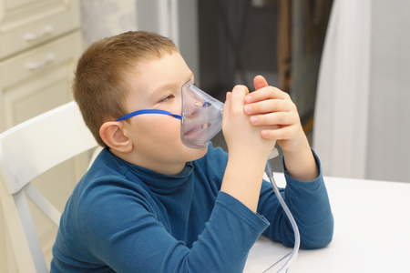 the boy treats a cold with an inhalerの写真素材