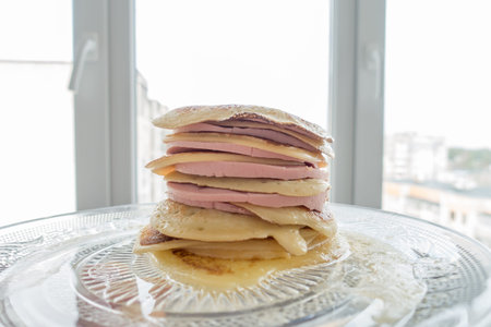stack of pancakes with a layer of sausage pieces on a plate