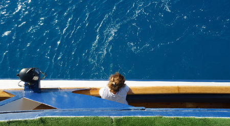 girl looks from the lower deck of the ship to the sea