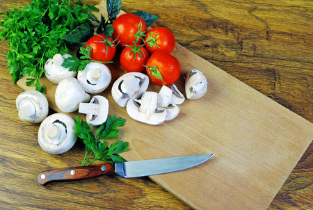 Fresh mushrooms and ripe tomatoes on a cutting boardの写真素材