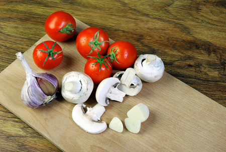 Fresh mushrooms and ripe tomatoes on a cutting boardの写真素材