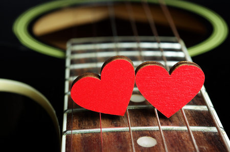 Red hearts on the strings of a guitar. Hearts are a symbol of love. Valentine's Day. Strings of the...