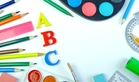 School supplies. Pencils, paints, eraser, pens, brushes and letters on a white background. Beginning of the school year. Copy spaces.の写真素材